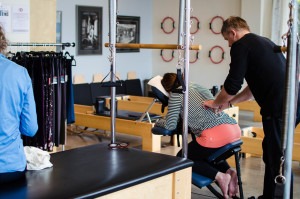 Dan, from Sattva Healing Arts, offers a chair massage as others explore the Pilates equipment.